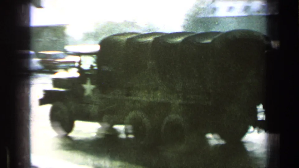 Side view of a canvas-covered military truck with a white star marking, caught in bright exposure on an 8mm home-movie frame.
