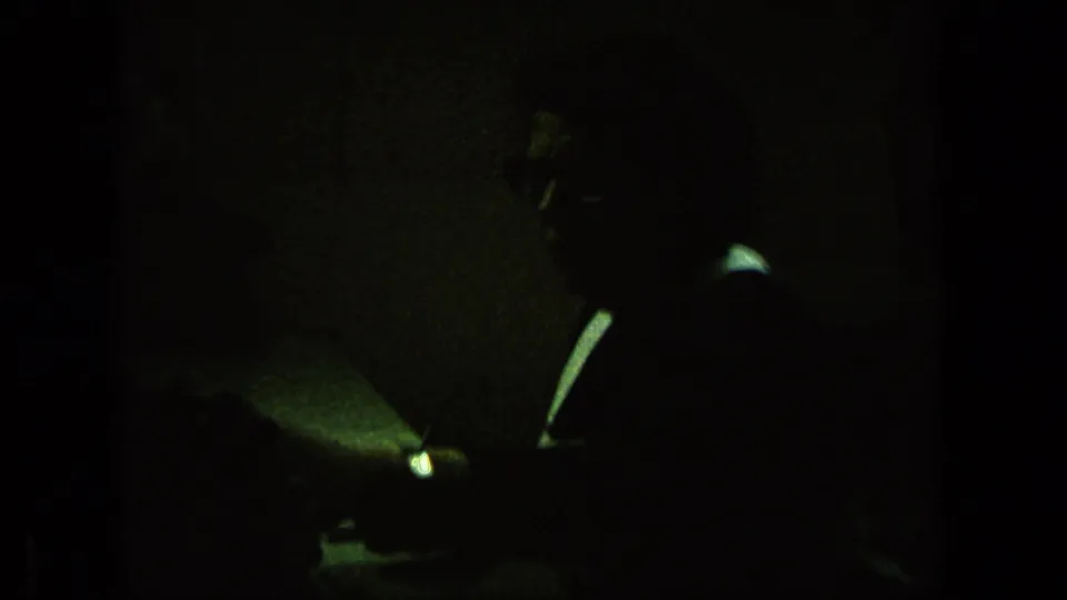 Underexposed final frame from the 1963 Germany clip, with a dark vehicle shape and limited street detail visible through grain and shadow.