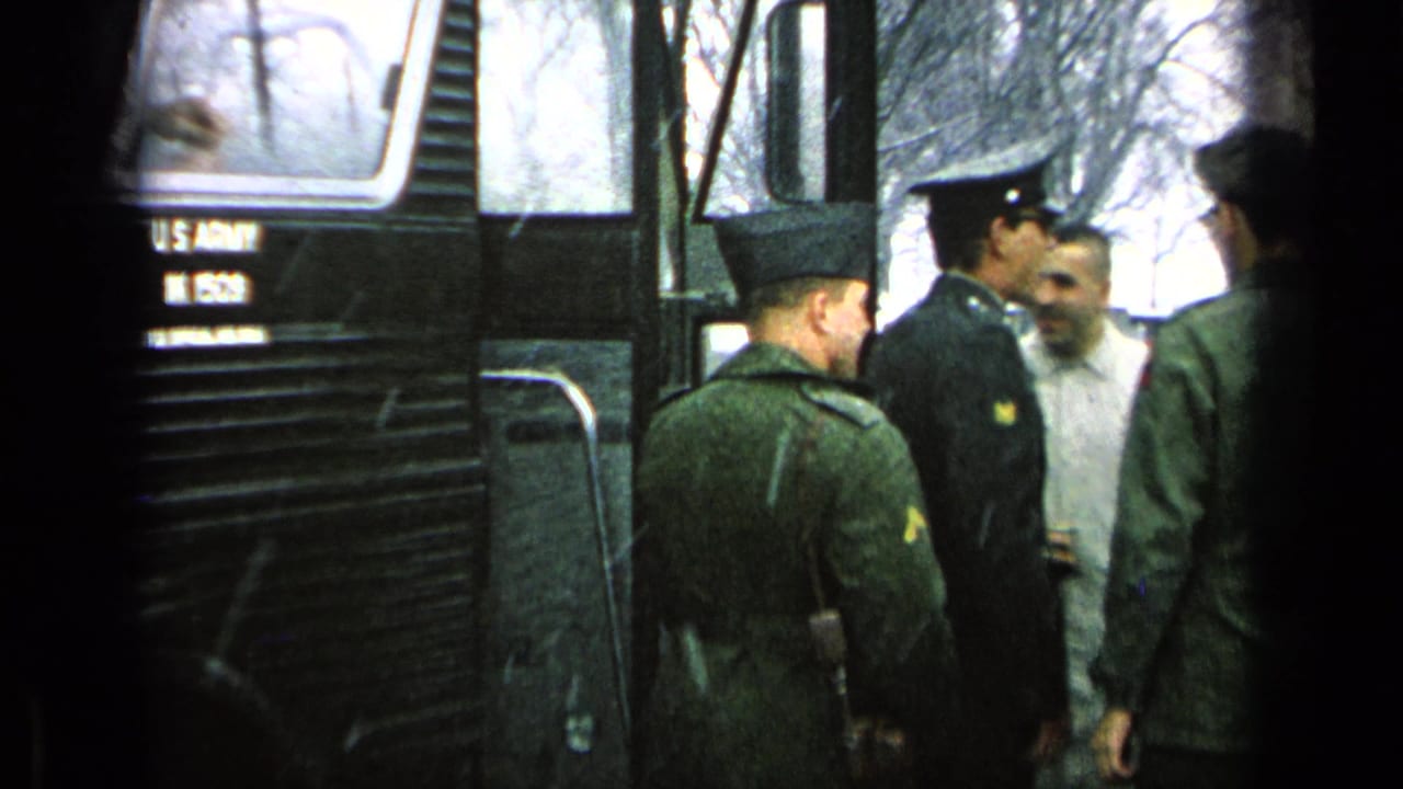 Uniformed soldiers standing beside a dark U.S. Army bus with an open door.