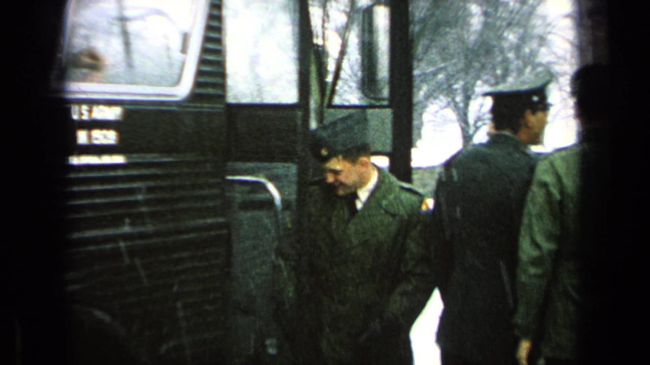 Soldiers in caps move along the side of a marked U.S. Army bus.