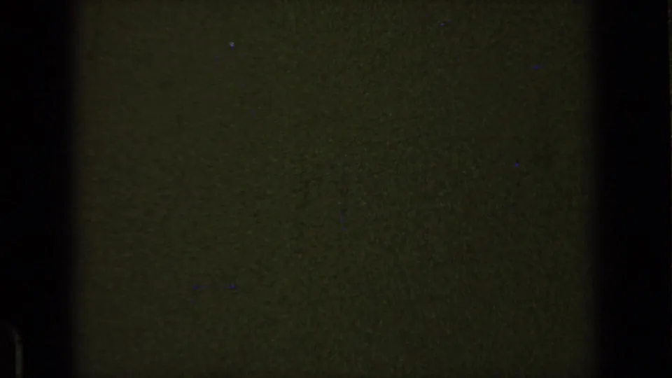 End frame from the 8mm clip showing dark underexposed film texture, grain, and black edge areas rather than a clear scene.