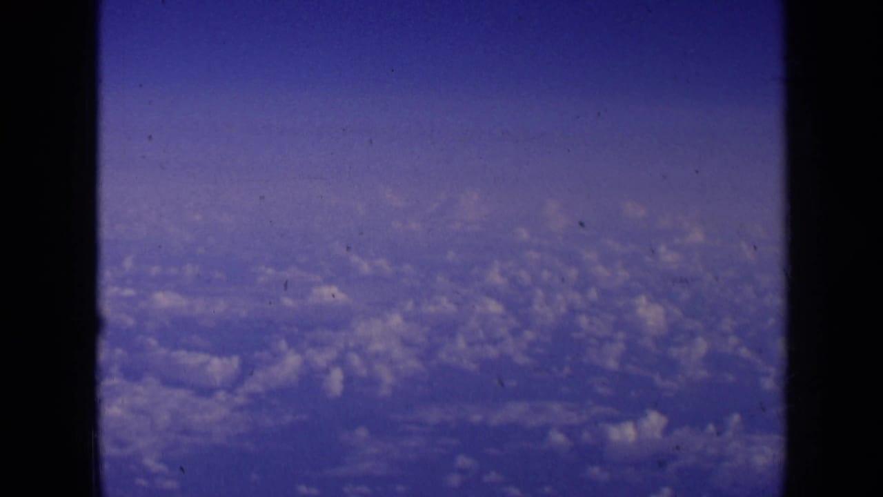 1963 8mm aerial view over cloud fields, likely filmed from a passenger aircraft window during travel associated with London metadata.