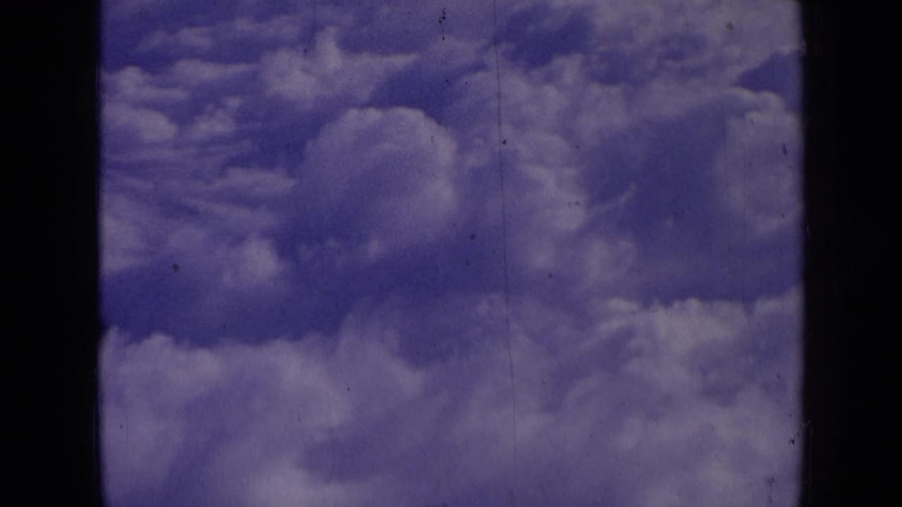 Cloud banks under a blue-purple sky with dark vertical film borders.