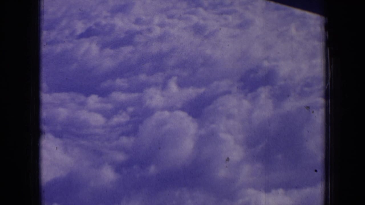 Blue sky and puffy cloud layer framed by a dark window edge.