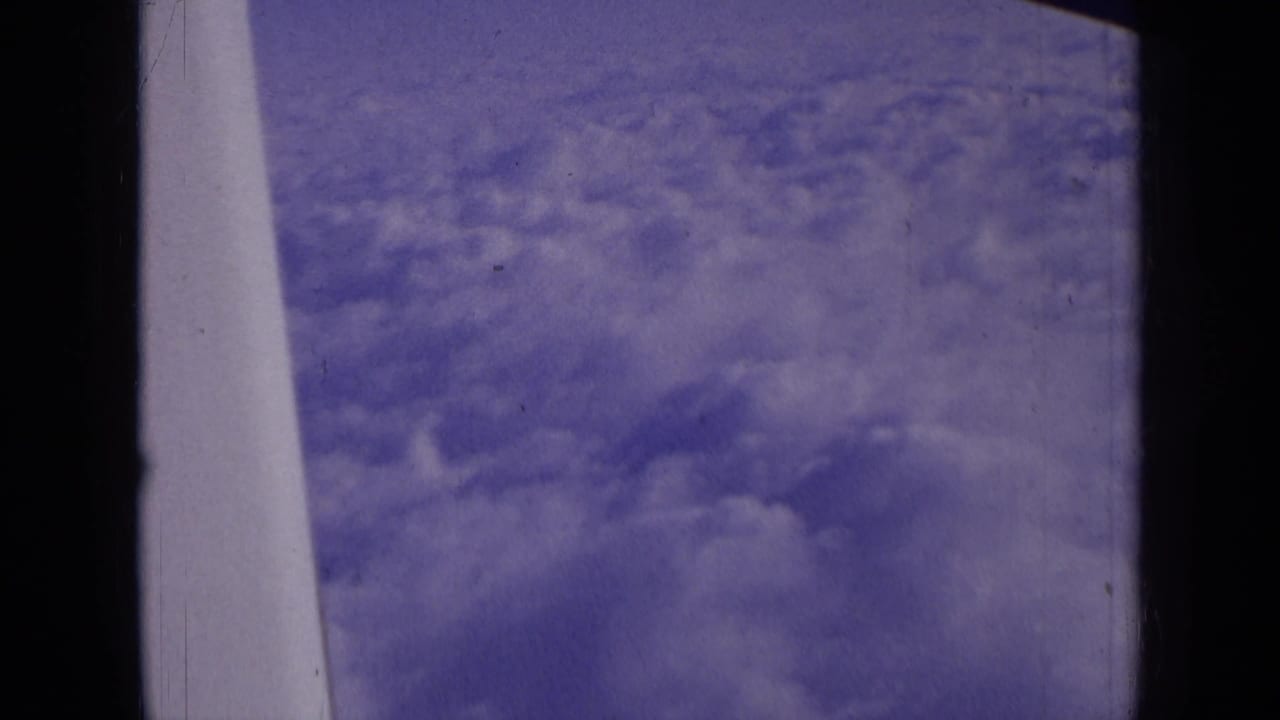 Cloud cover through an airplane window with a pale aircraft edge near the center-left.