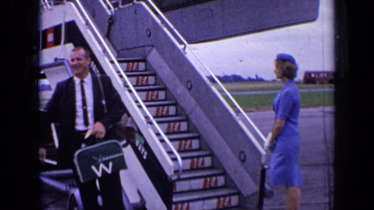 A suited passenger descends BEA aircraft stairs as a blue-uniformed attendant stands on the tarmac in London, 1963.