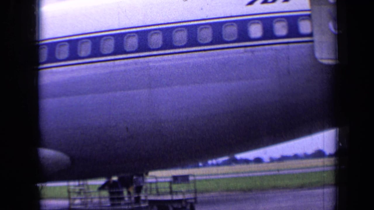Close view of a Sabena aircraft fuselage with windows, wing edge, tarmac, and dark foreground borders.