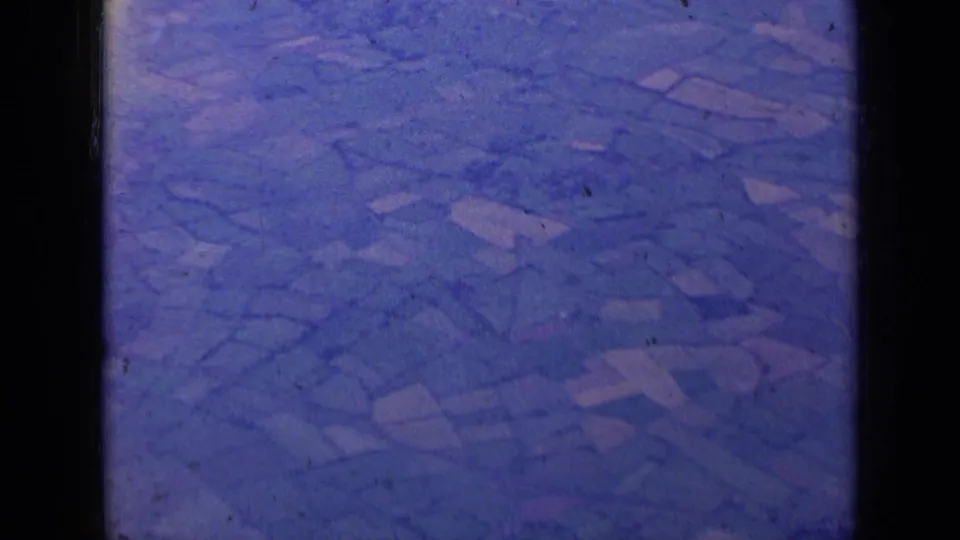 1963 home-movie frame showing a blue-tinted aerial view of fields, framed by dark contact-sheet borders.