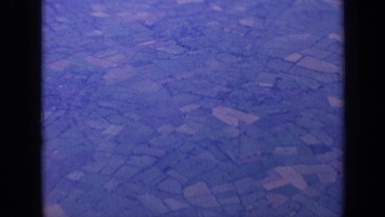 Blue-tinted aerial view of patchwork farmland through dark aircraft-window framing.