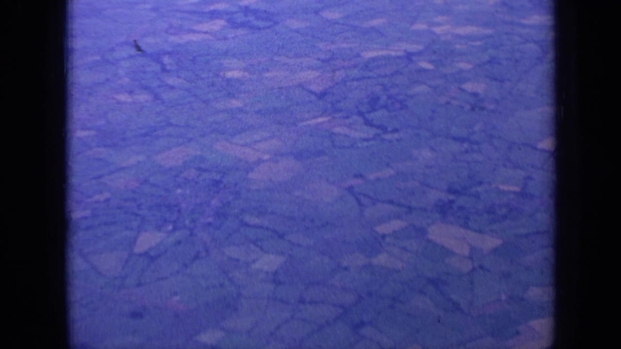 Aerial farmland pattern with hedgerows, soft focus, and dark vertical window borders.