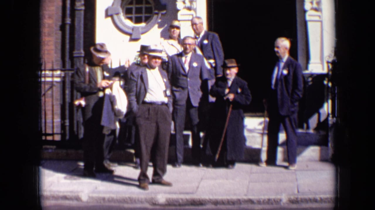 Men in suits and hats stand outside an ornate building entrance.