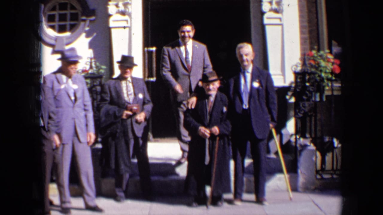 Five adult men in suits stand on steps outside a decorative doorway.