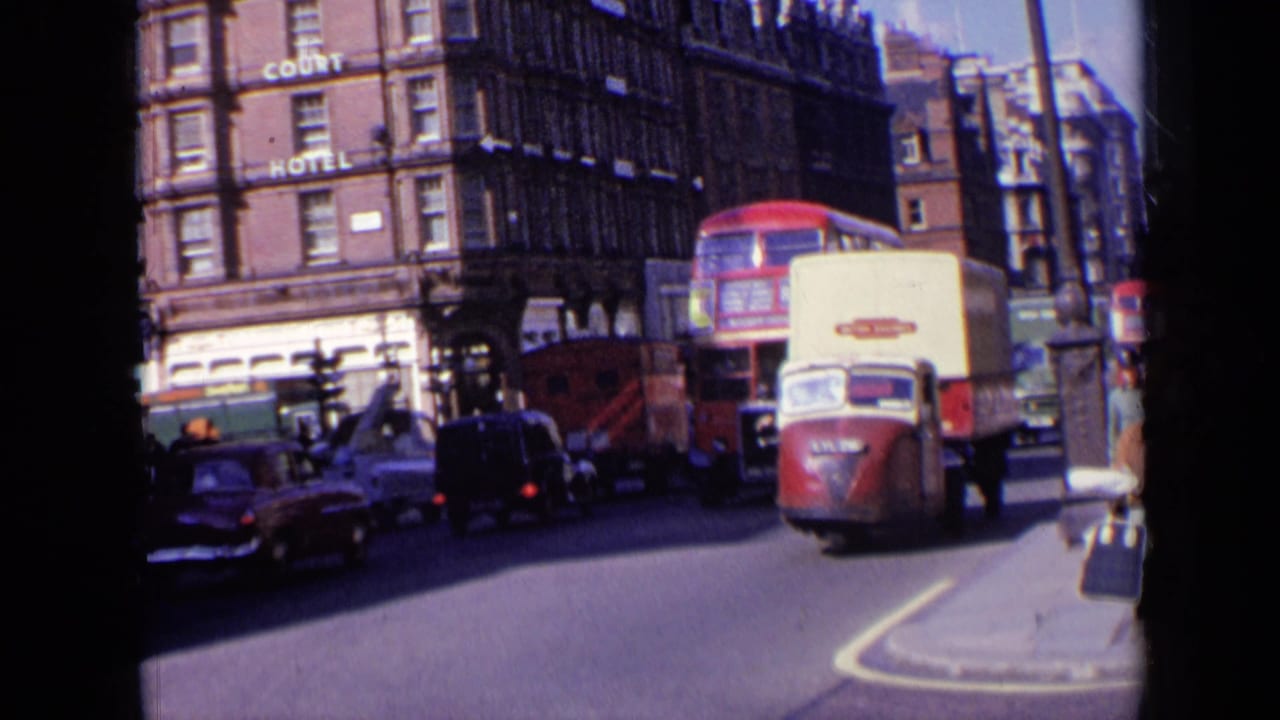 Red double-decker bus and delivery van in heavy traffic near a brick hotel building.