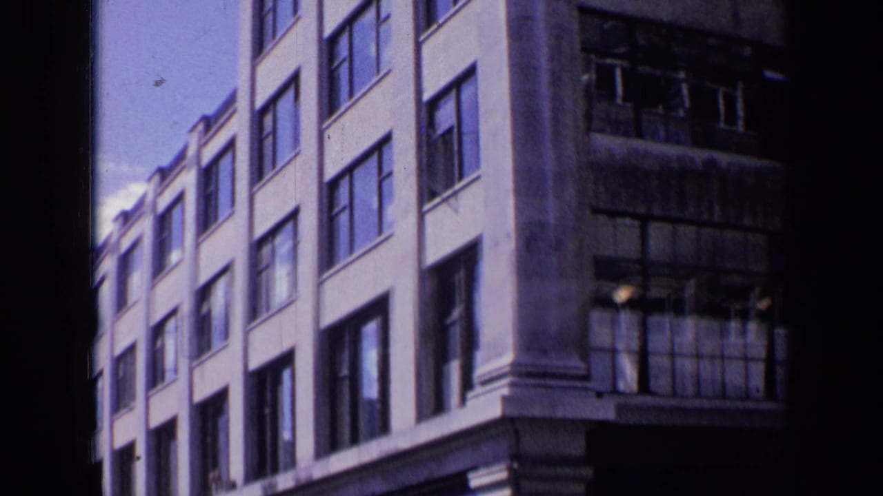 Pale multi-story building beside a darker facade with broken windows.