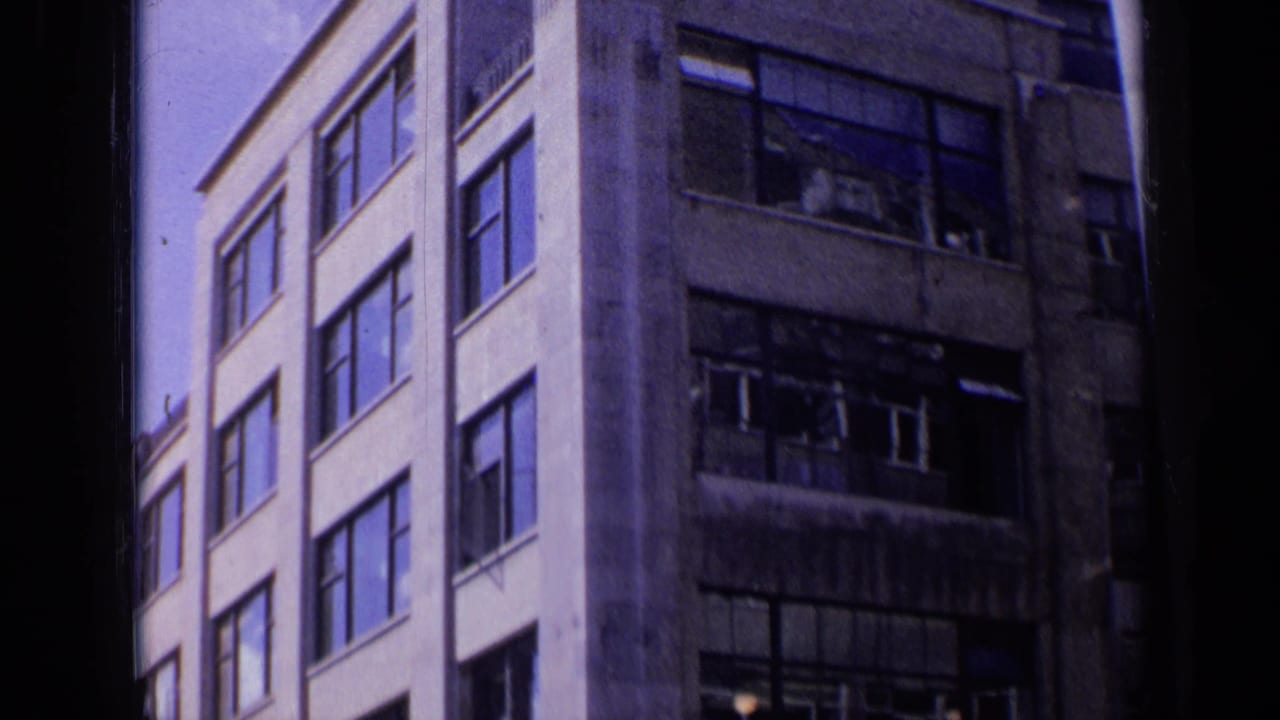 Two adjacent multi-story buildings with large windows and damaged upper panes.