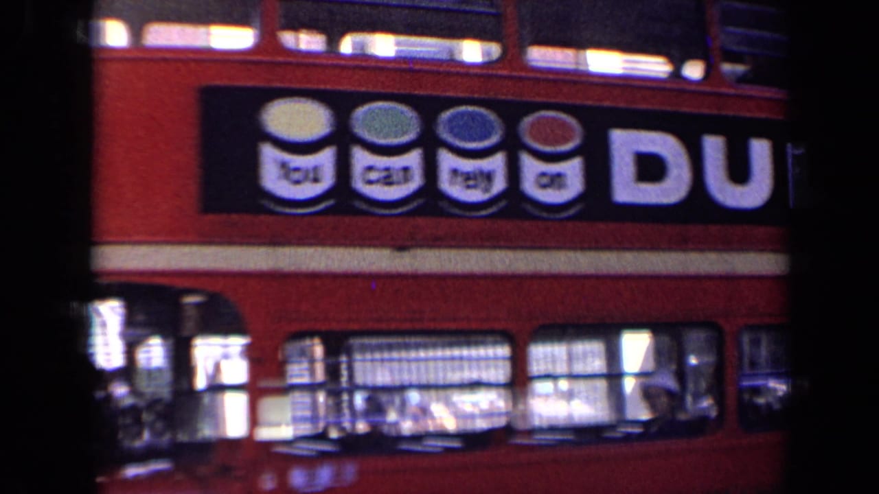 Close view of a red double-decker bus with Dulux advertising passing in a London street.