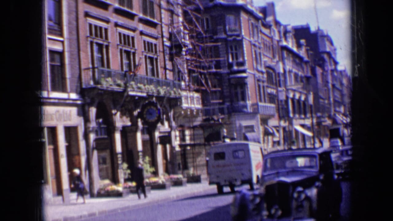 London street with ornate buildings, pedestrians, a white van, and a dark car approaching.