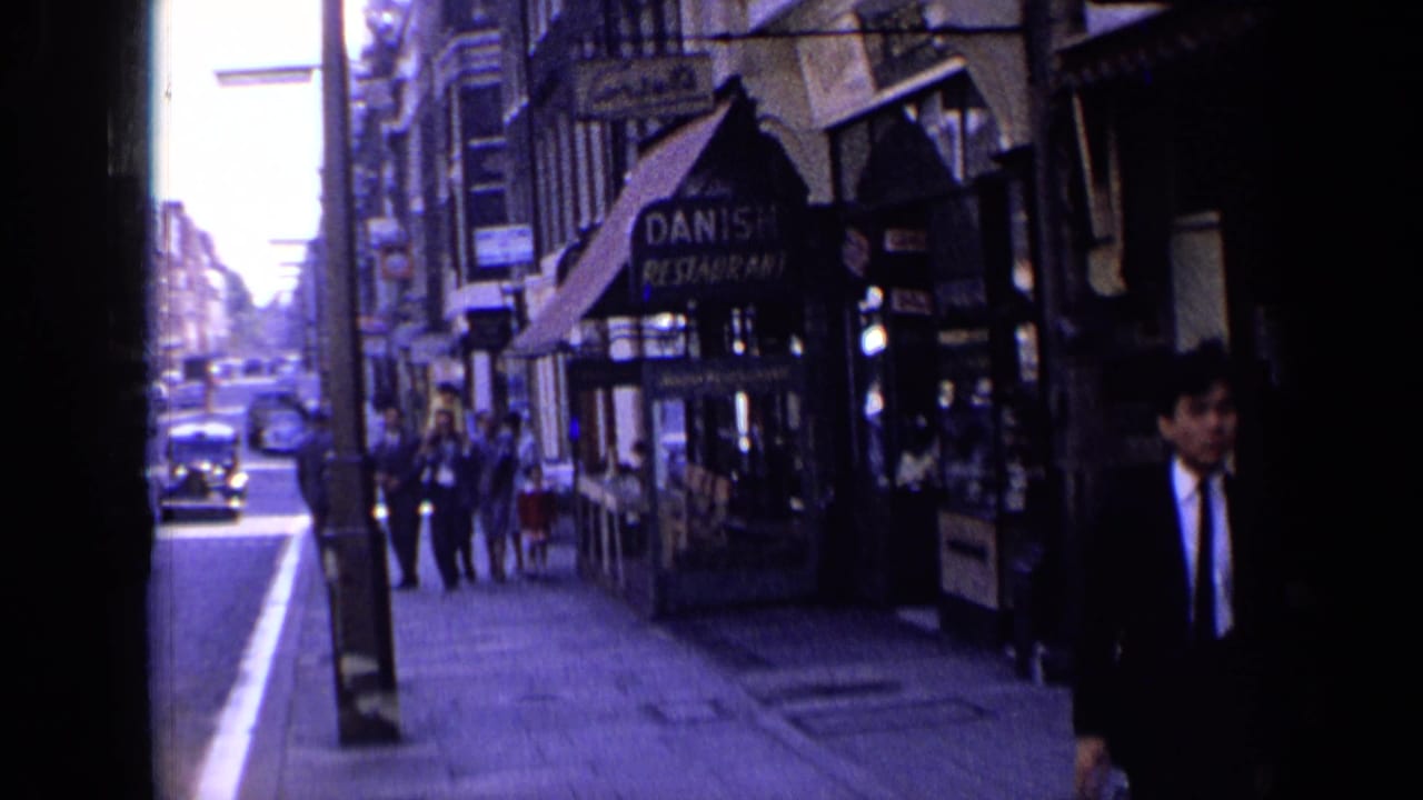 Right side of street with Danish restaurant awning, pedestrians, and approaching cars.