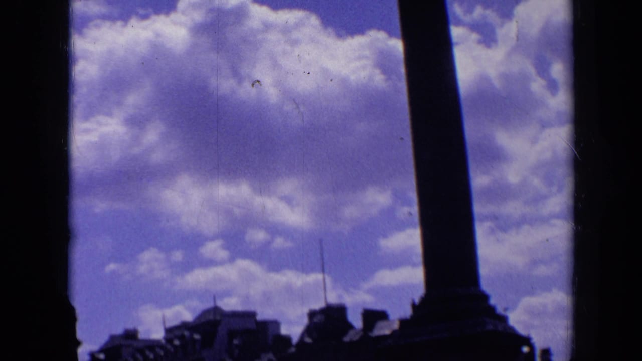 Tall column silhouette above Trafalgar Square buildings and clouded sky.
