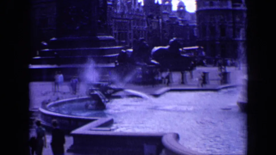 Trafalgar Square in London, filmed on 8mm in 1963, with fountain water, scattered visitors, stone basins, and urban buildings visible.