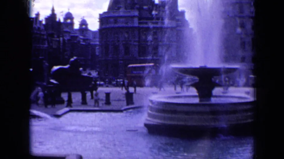 A 1963 London square scene frames the fountain basin at right with people and traffic moving near ornate buildings.
