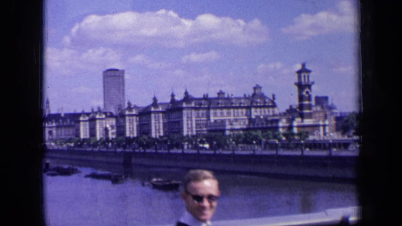 London riverfront buildings and boats with a suited man partly visible in the foreground.