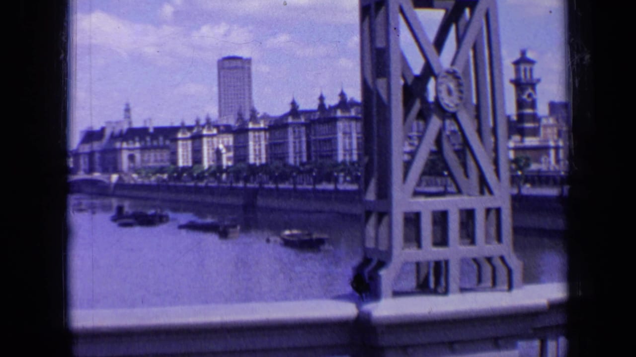 Bridge structure framing a river view of London buildings and small boats.
