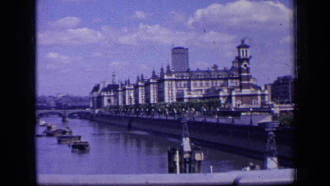 Similar Thames view with boats near a bridge and a long building beside the river.