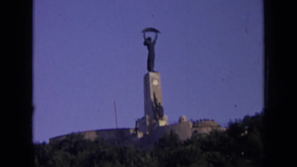 1963 8mm Russia footage showing a distant low-angle view of a metal figure atop a stone monument on a hill.