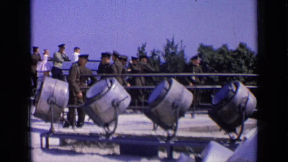 A 1963 Russia overlook scene with uniformed men near a railing and three large searchlights in the foreground.