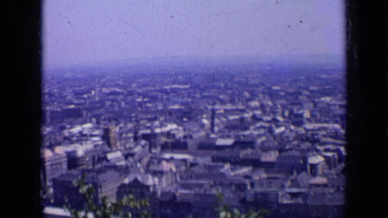 1963 Russia 8mm frame showing a broad urban skyline from an elevated viewpoint under a pale hazy sky.