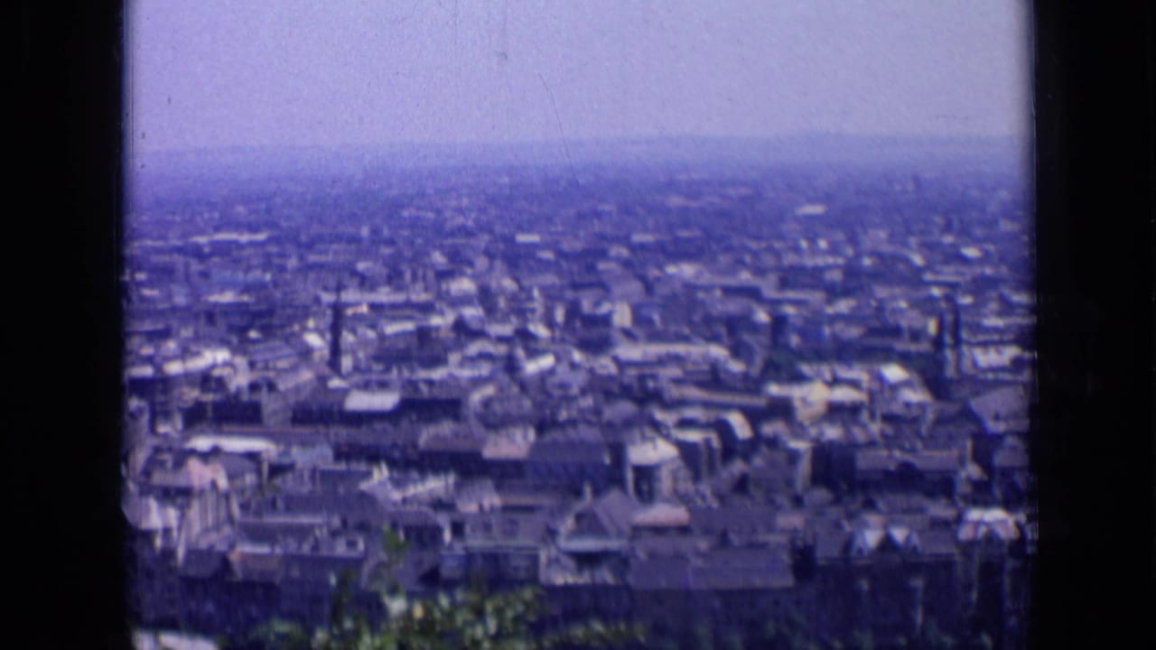 Wide urban view with dense buildings, hazy horizon, and vertical film-frame divider.