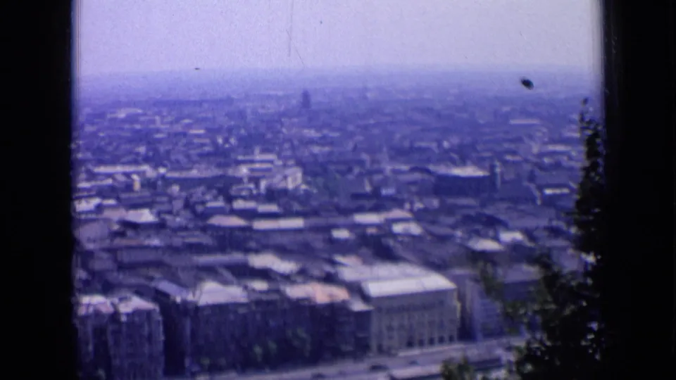 1963 Russia home-movie frame showing rooftops, streets, and larger buildings beneath a hazy urban horizon.