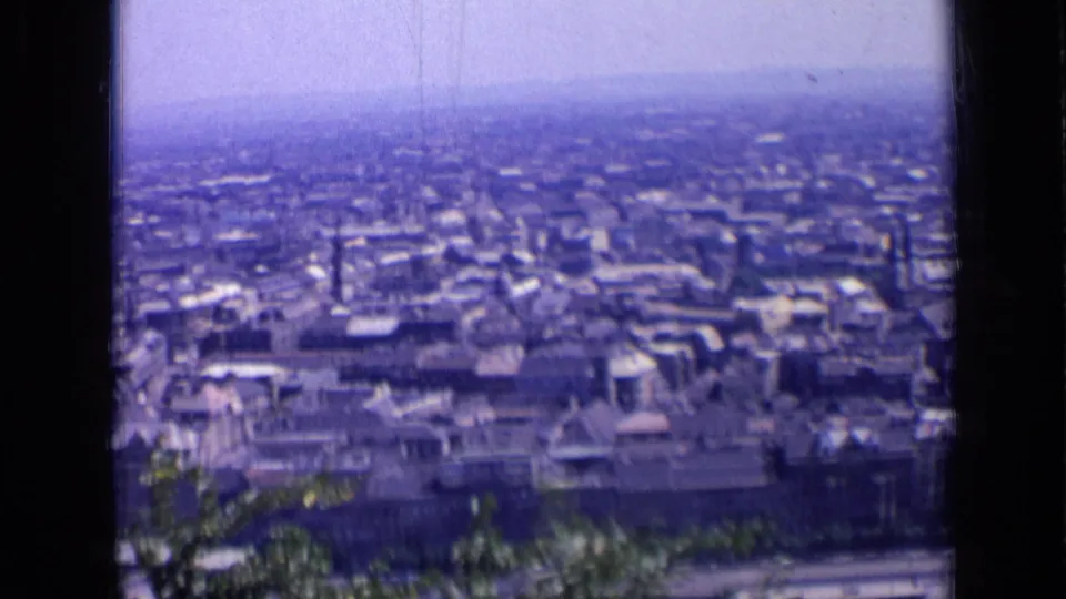 Blue-cast 1963 Russia city overlook with rows of buildings, a hazy horizon, and dark 8mm frame borders.