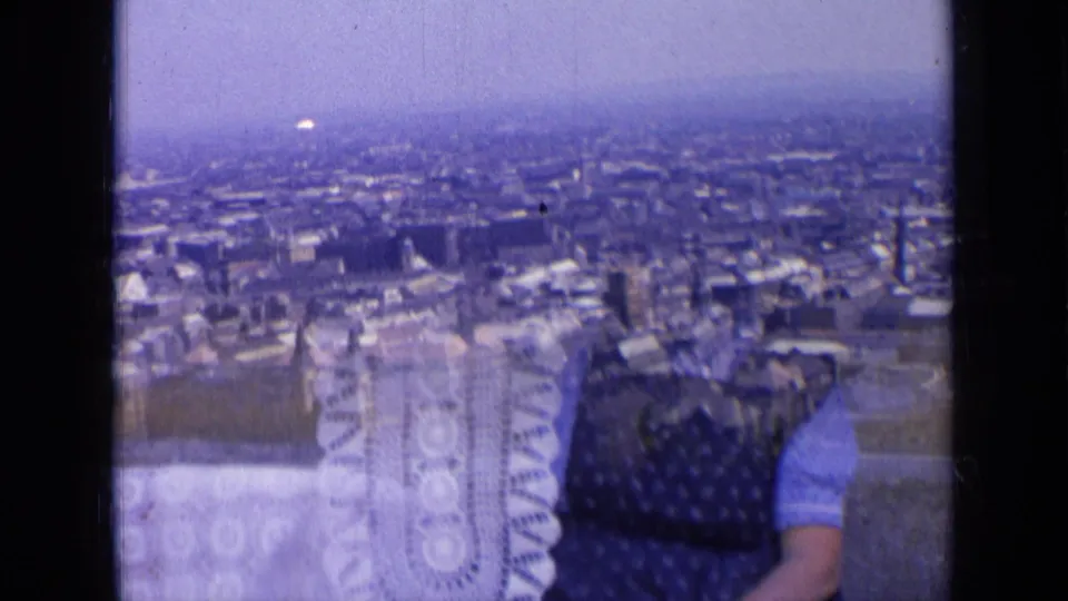 1963 Russia frame with city rooftops in the distance and a partially visible woman holding a pale crocheted or patterned textile.