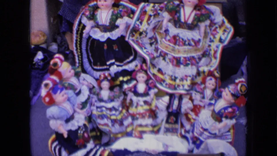 Close 8mm view of Russian folk-style dolls in bright dresses and headscarves arranged on a vendor display.