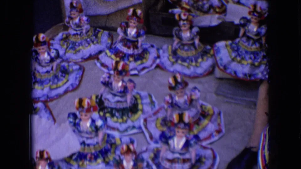The camera frames the tabletop display of Russian folk-style dolls, showing layered skirts, bright trim, and several small figures.