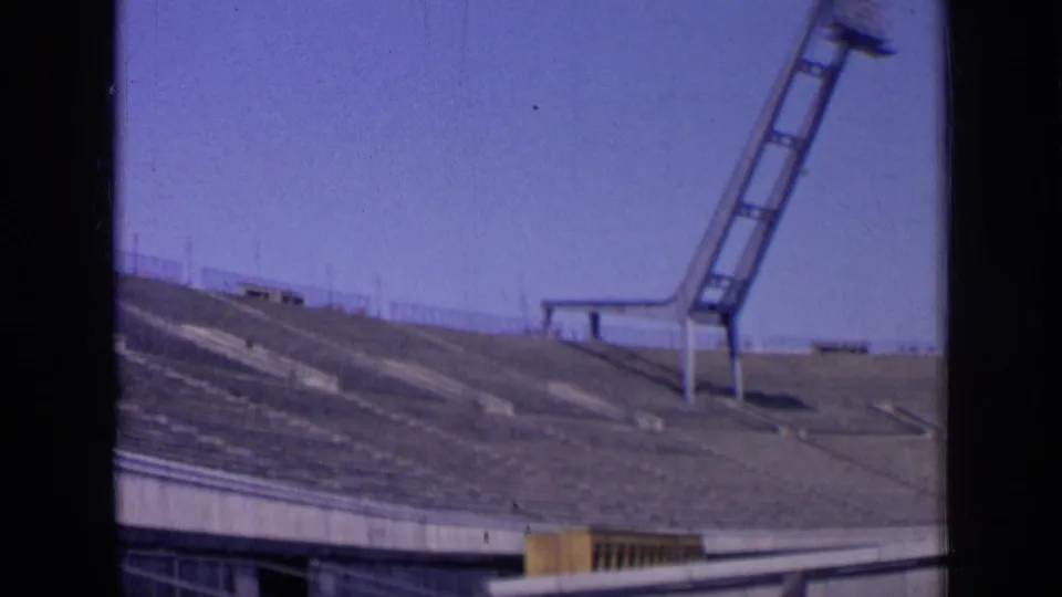 1963 Russia stadium view with empty tiered seating and a tall floodlight mast silhouetted against blue sky.