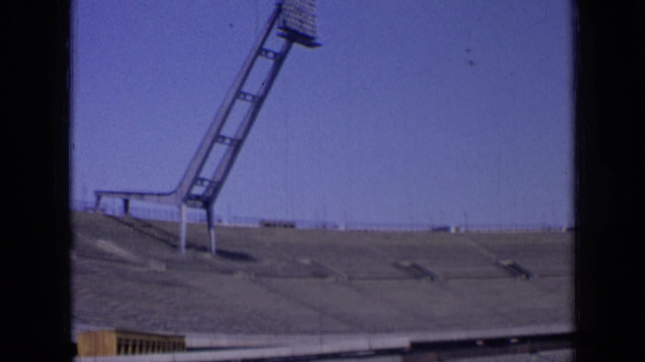 Stadium roofline and floodlight mast viewed from across empty seating.