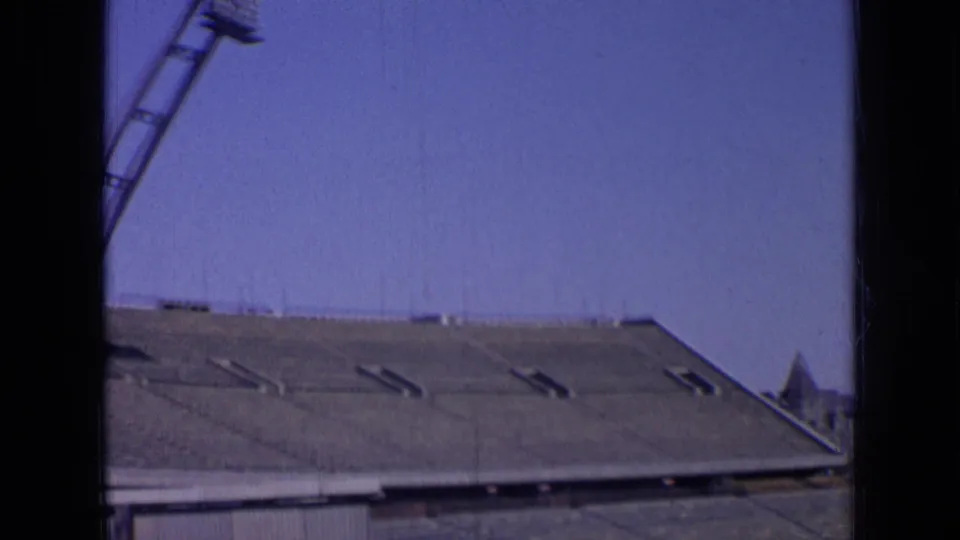 1963 Russia 8mm frame panning across empty stadium seating with distant structures on the horizon.