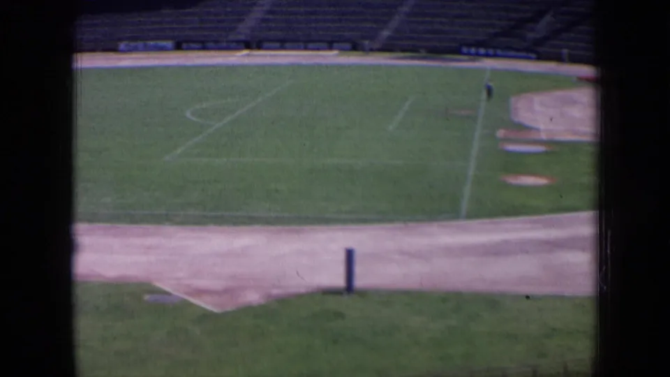 1963 Russia 8mm frame of an empty football field bordered by a paved track area and tiered concrete seating.