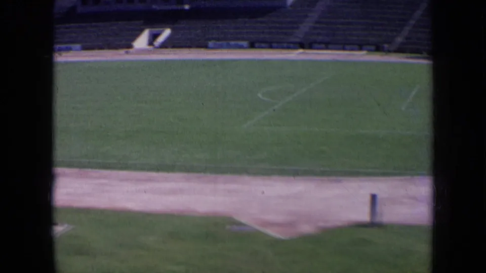 1963 Russia 8mm view of a stadium field through dark window bars, showing green turf, track edge, and empty seating.