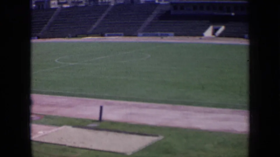 1963 Russia stadium view through dark framing, with a green field, pale track, empty stands, and stadium access opening.