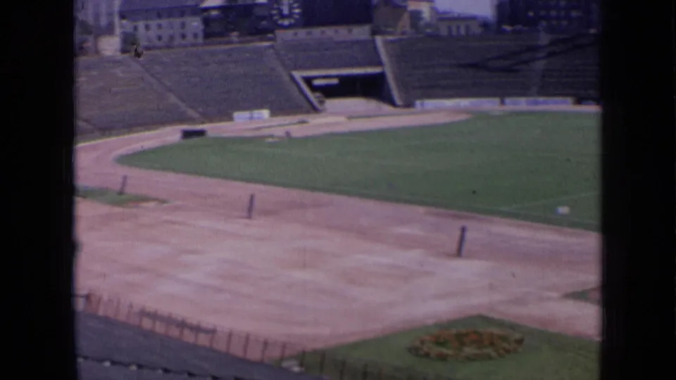 1963 Russia stadium frame with track curve, field edge, empty stands, access tunnel, and a small foreground flower bed.