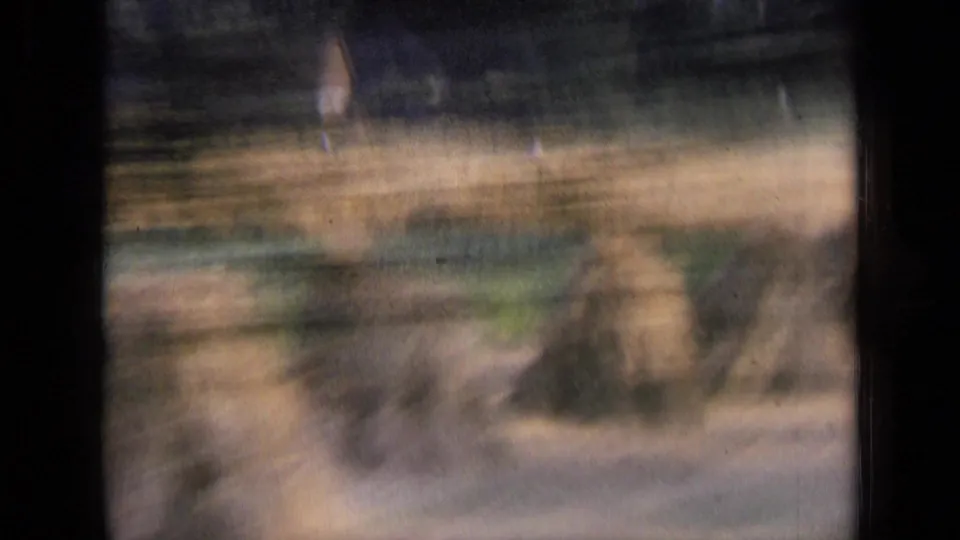 A blurred rural field with possible haystacks passes the camera during the 1963 Russian road trip sequence.