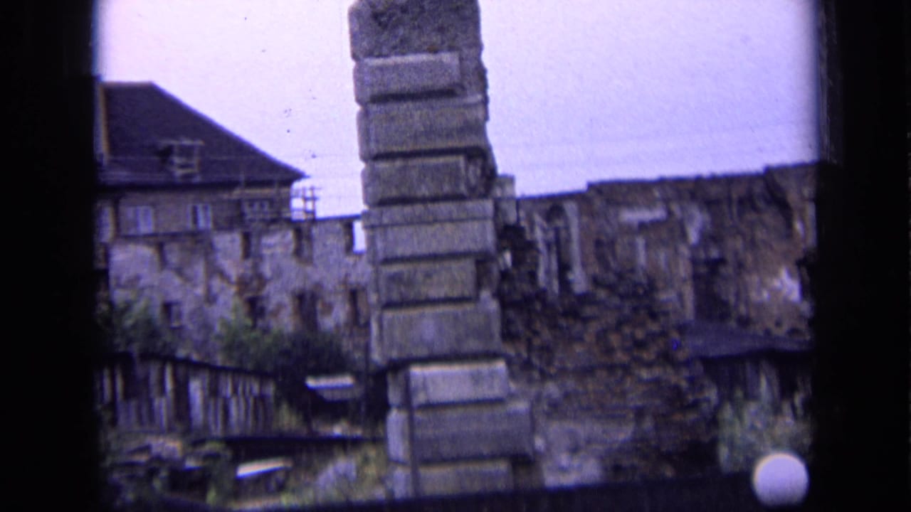 1963 Russia 8mm view of weathered stone ruins with a tall masonry stack, partial wall, trees, and a low building edge.