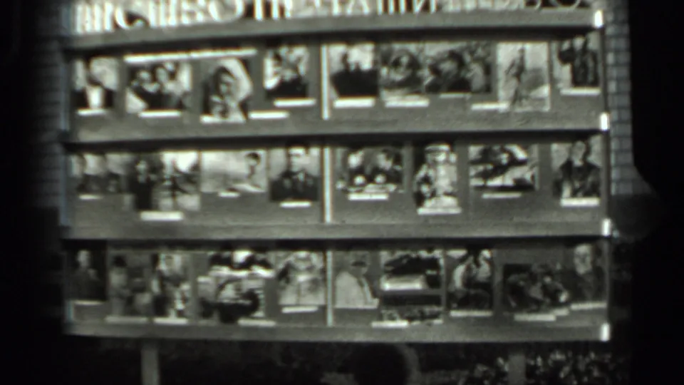 1963 Russia 8mm frame showing a public magazine or photo display with Cyrillic signage and several rows of small printed images.