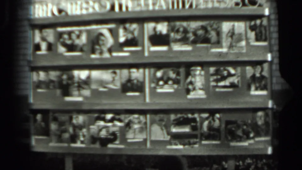 1963 Russia home-movie frame of a magazine or photograph stand, filmed from a fixed outdoor viewpoint in soft black-and-white focus.