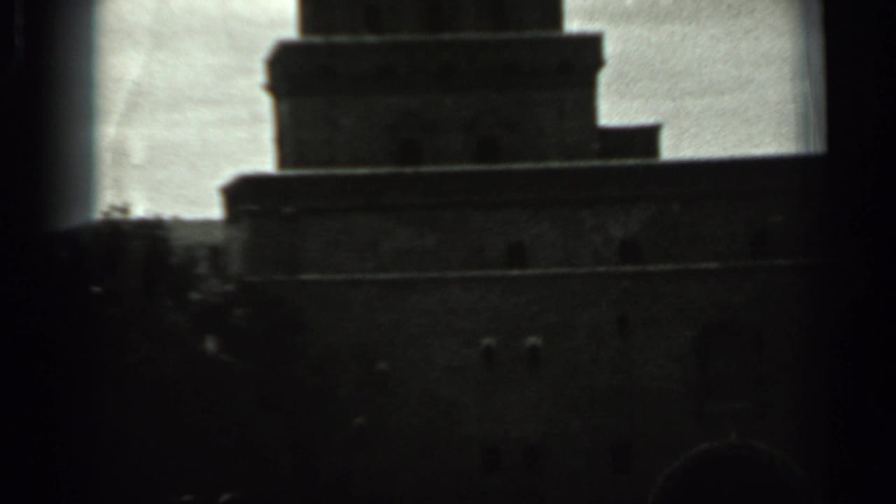 Dark stepped tower top silhouetted against a cloudy sky.
