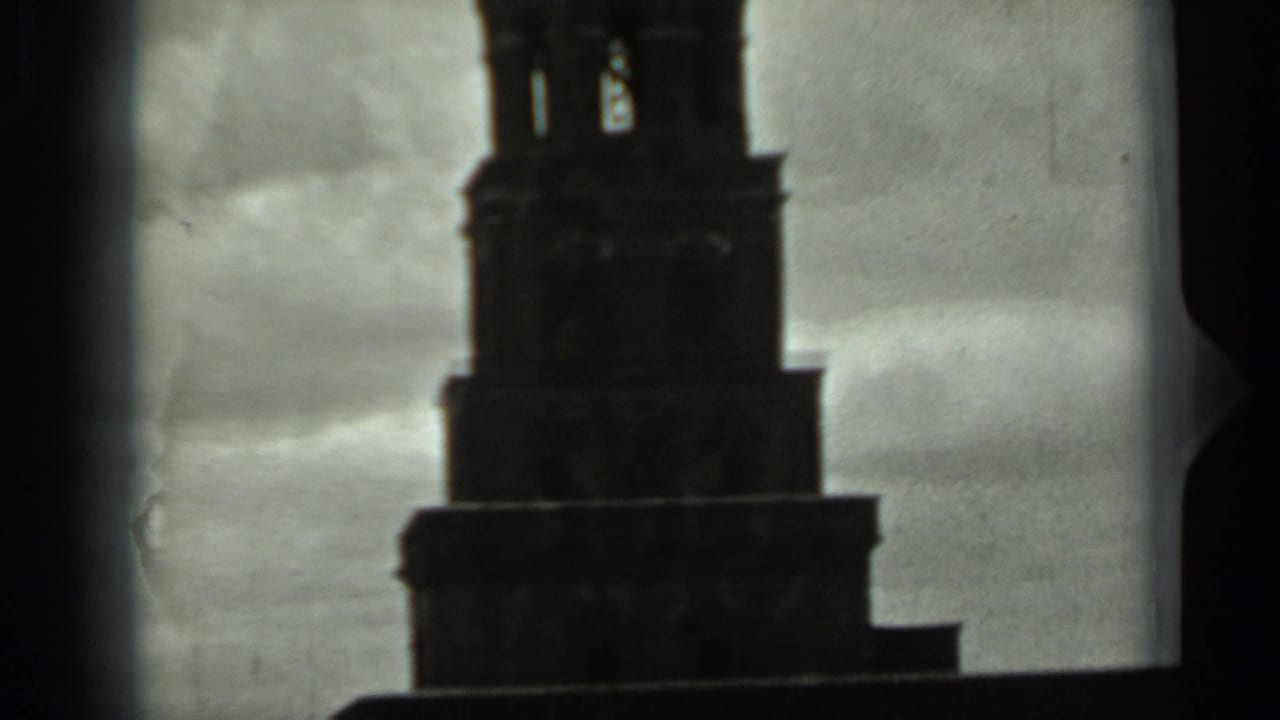 1963 Russia 8mm frame of a tall tower's upper tiers and open spire section silhouetted against a gray sky.
